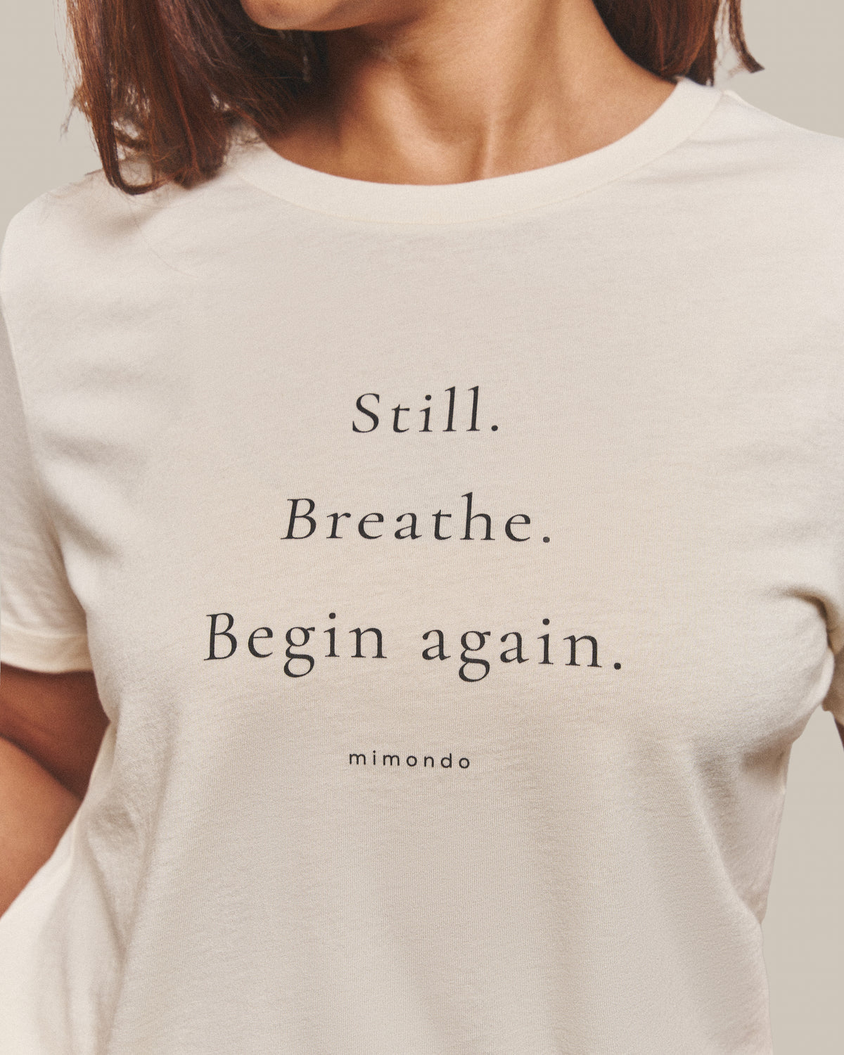 Close-up of the print on the Still Tee: Still. Breathe. Begin again. With mimondo printed beneath.