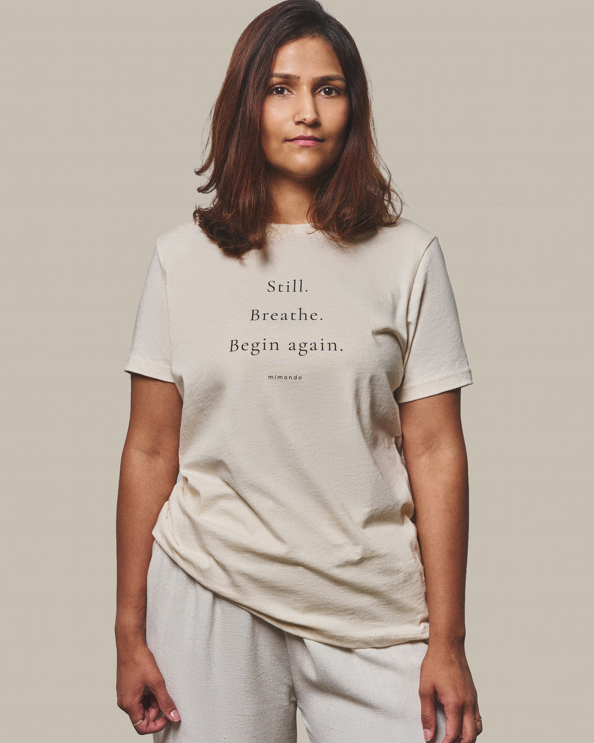 The Still Tee in Warm Ivory. The print reads: Still. Breathe. Begin again.